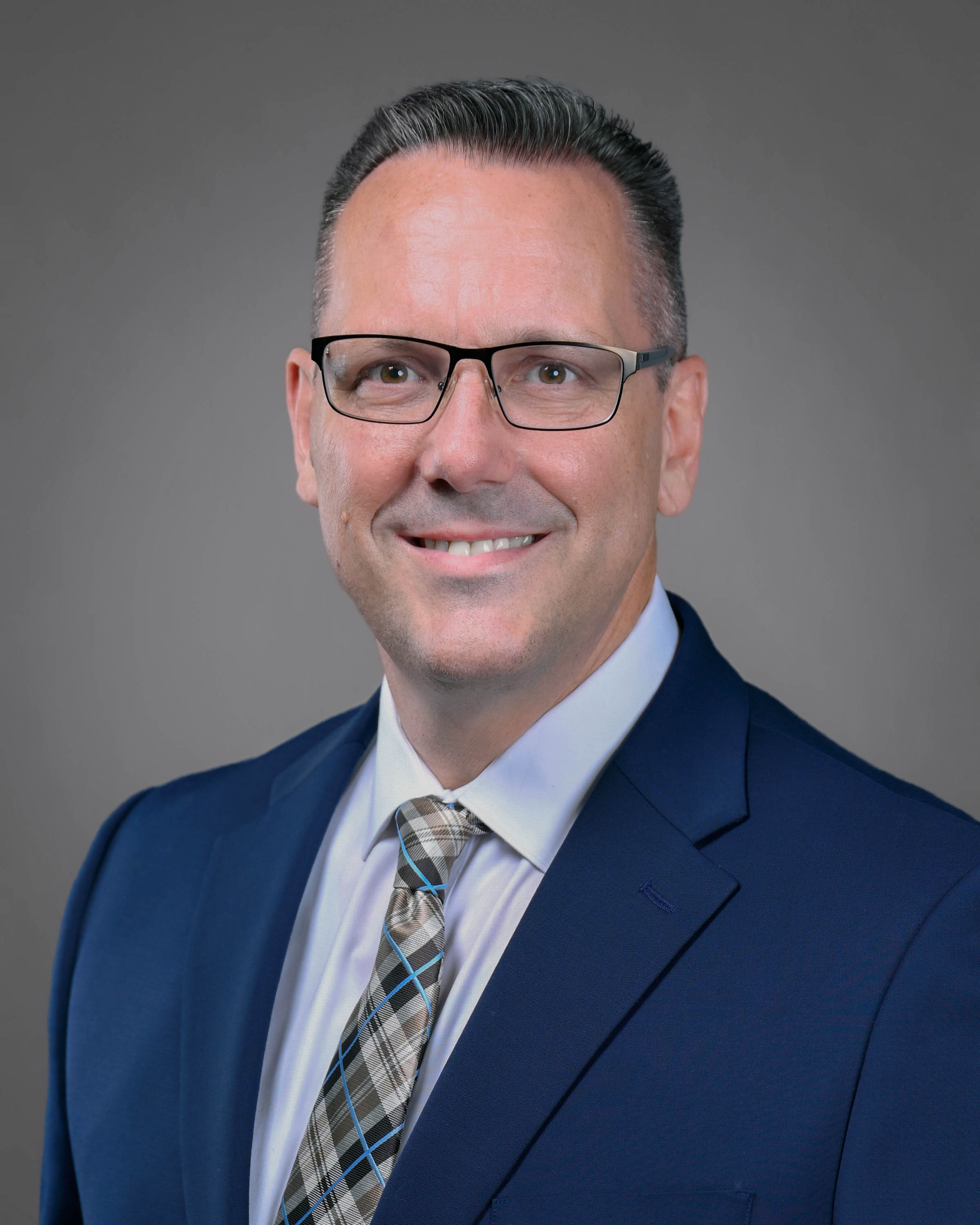 Smiling man with eyeglasses in a blue jacket with tie
